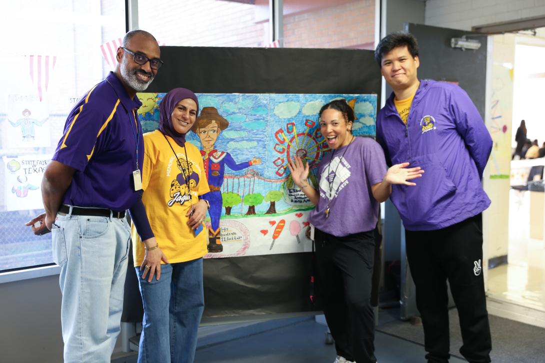 Four diverse teachers stand next to a large piece of art