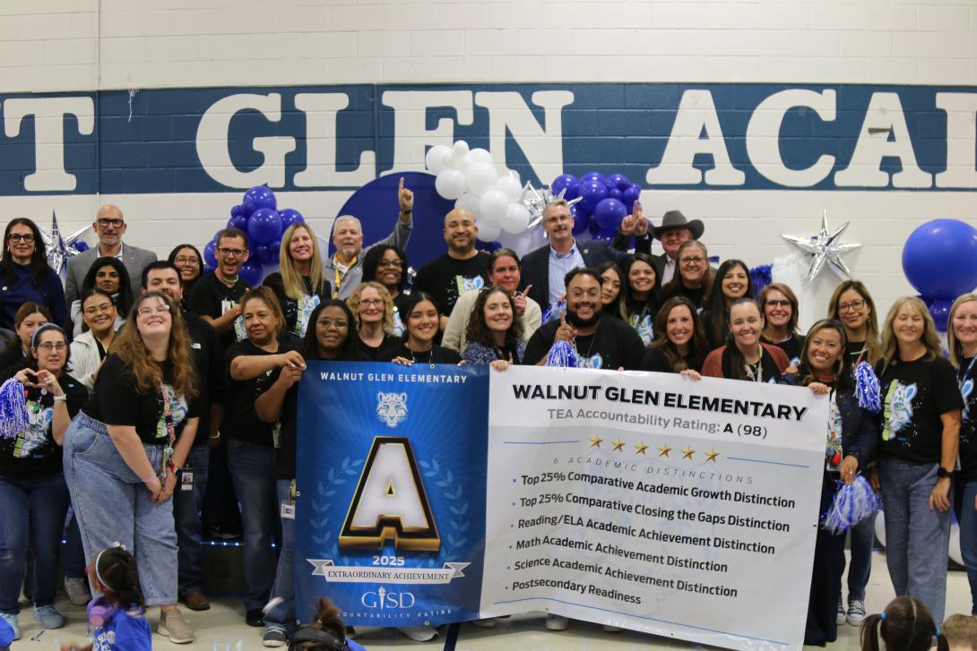 Teachers pose standing with a large banner