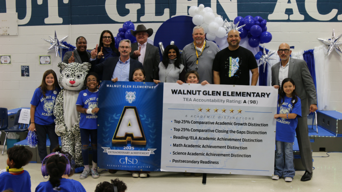 students and adults stand holding a large horizontal banner