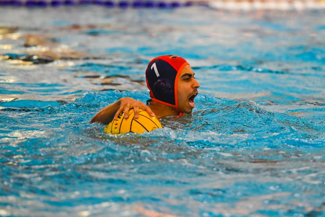 Male water polo player holds ball 