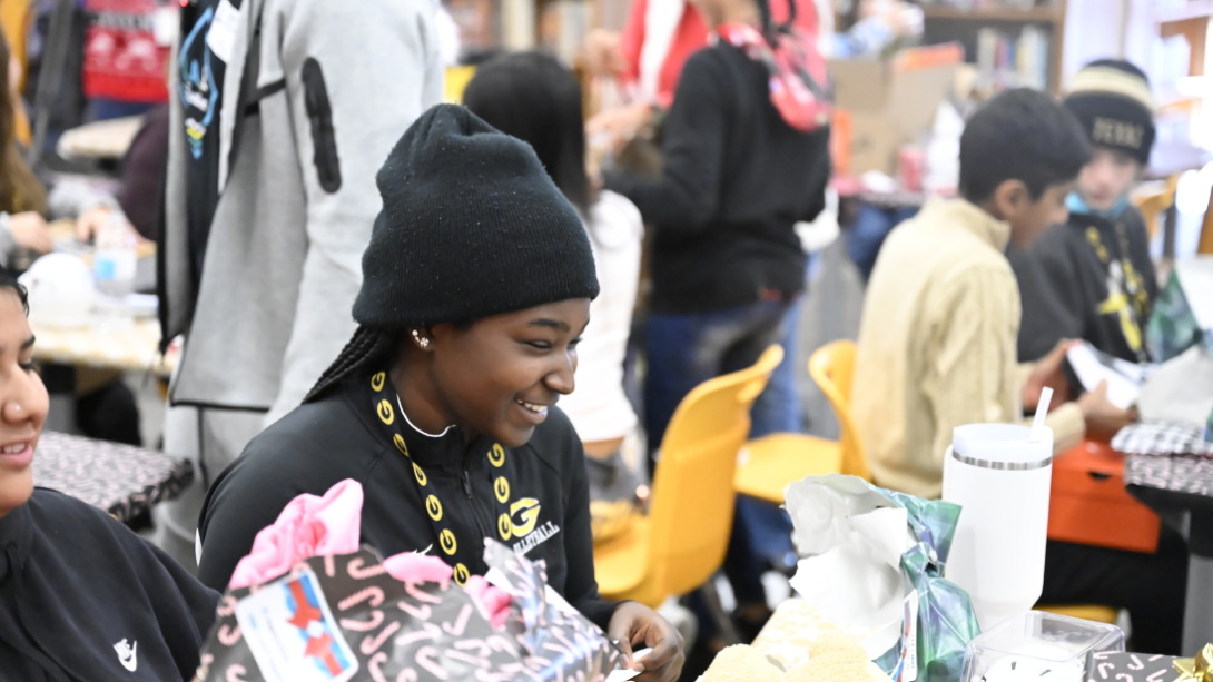 A student smiles as she opens a gift