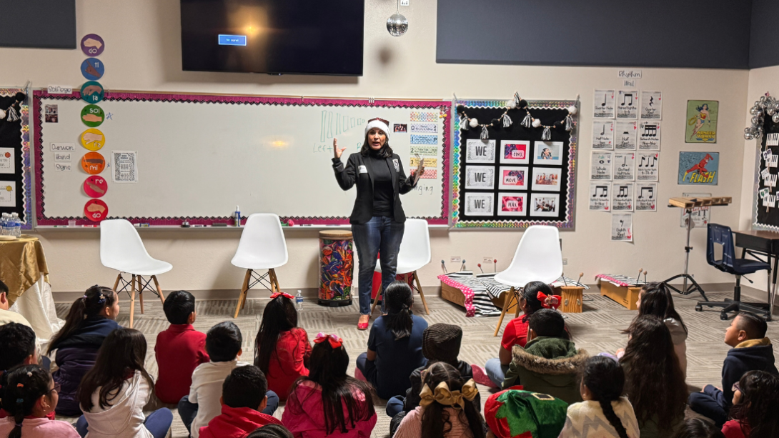 An adult woman reads to a group of students