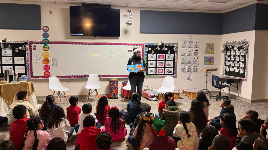 An adult woman reads to a group of students