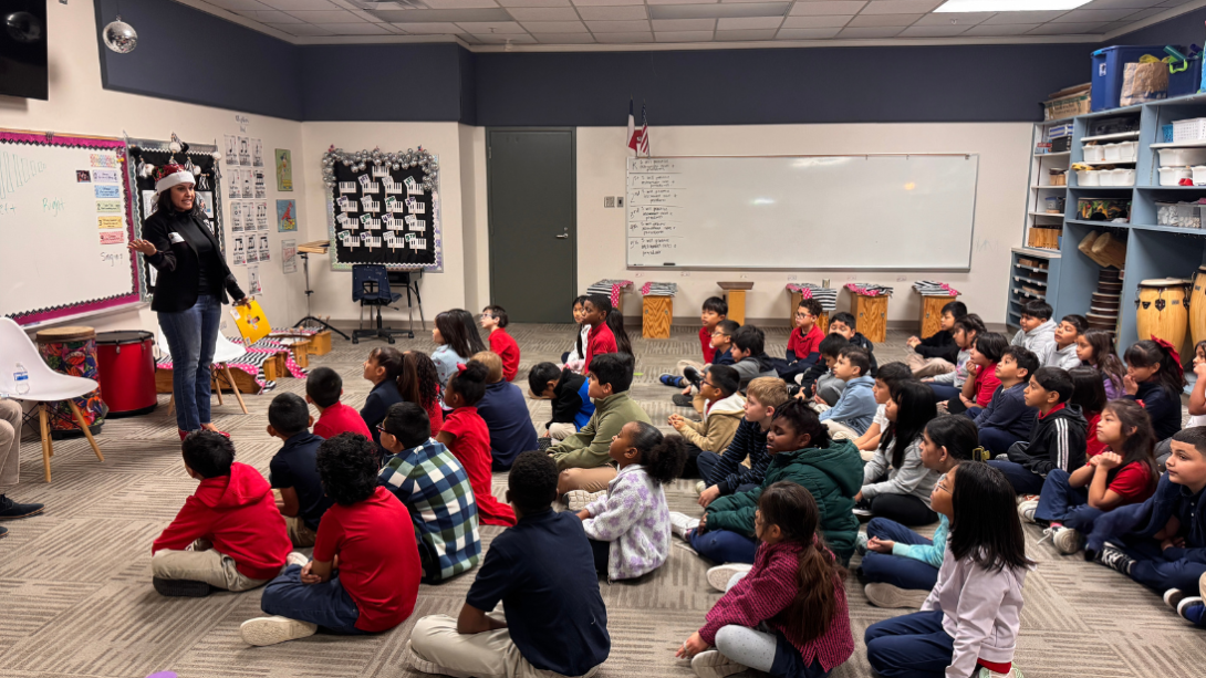 An adult woman reads to a group of students