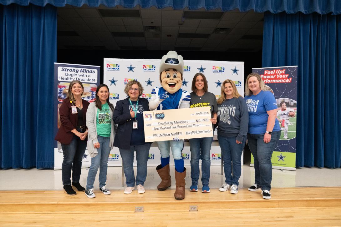 Dallas Cowboys mascot poses with a group of teachers, holding a large check