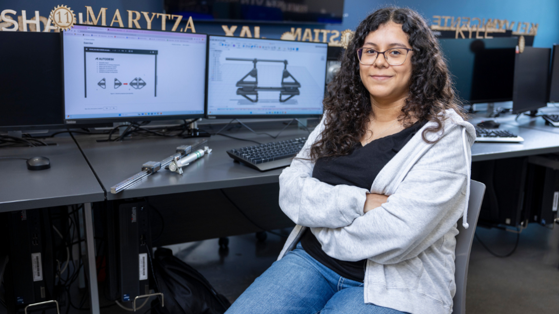 Female student sits with arms crossed in front of a computer screen