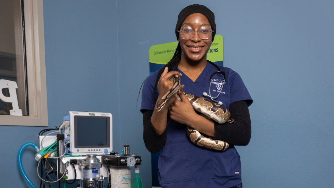 A female student stands holding a snake