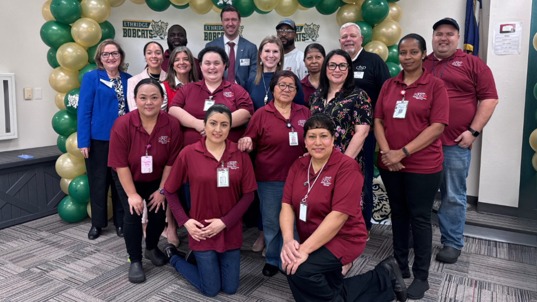 A diverse group of adults stand in front of a backdrop