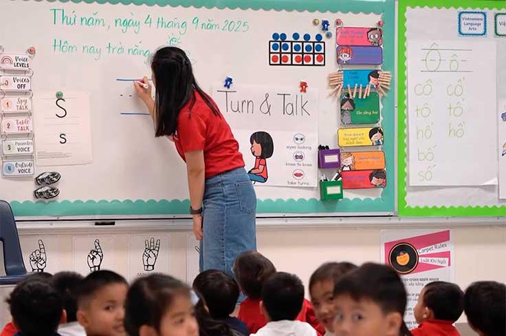 Teacher writing on the board while students look on in Vietnamese Dual Language elementary classroom 