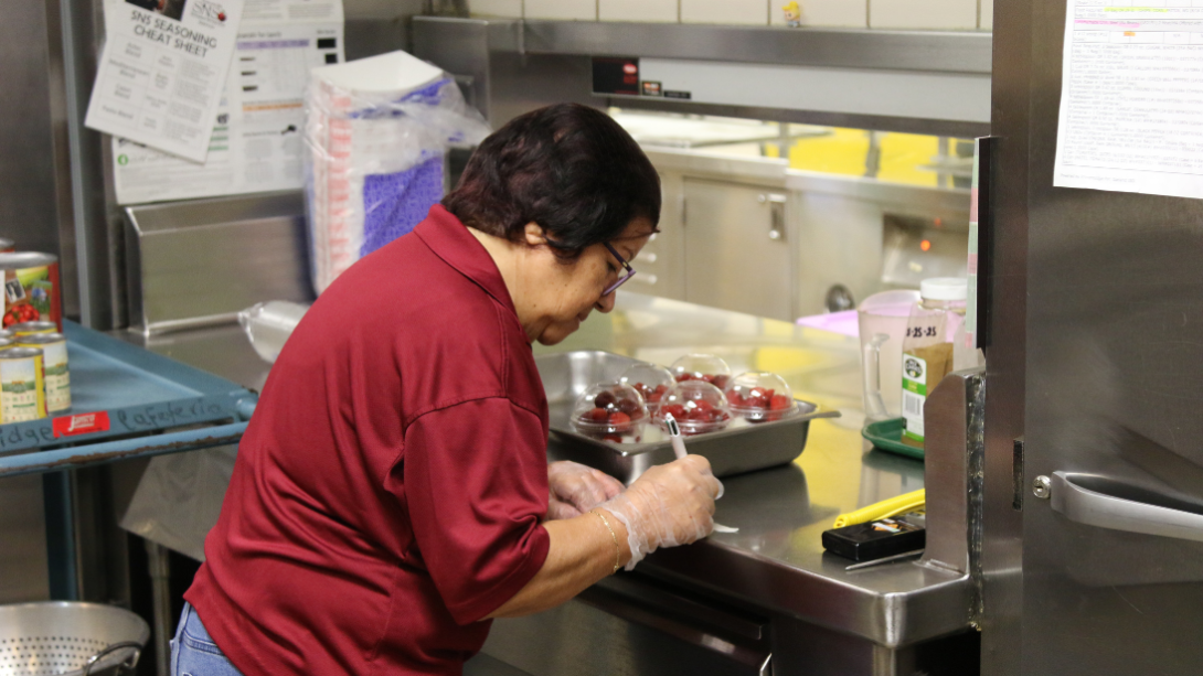 a cafeteria worker prepares labels for fresh food