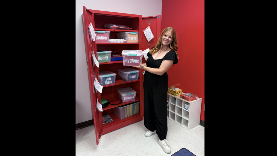 Female student stands in front of a large red filing cabinet