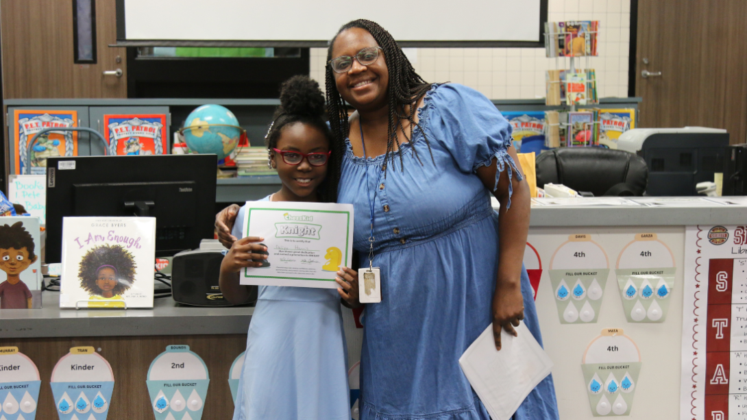 female student with certificate stands with female teacher