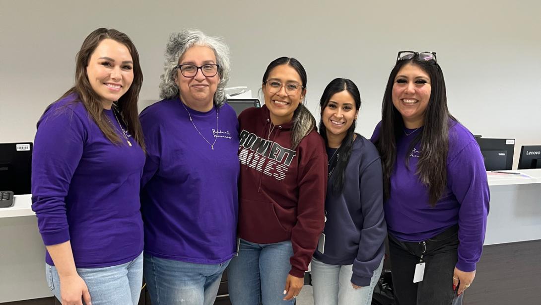 A group of employees smile in purple. 