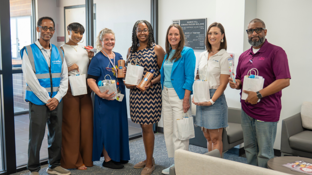 seven adults stand holding white paper bags