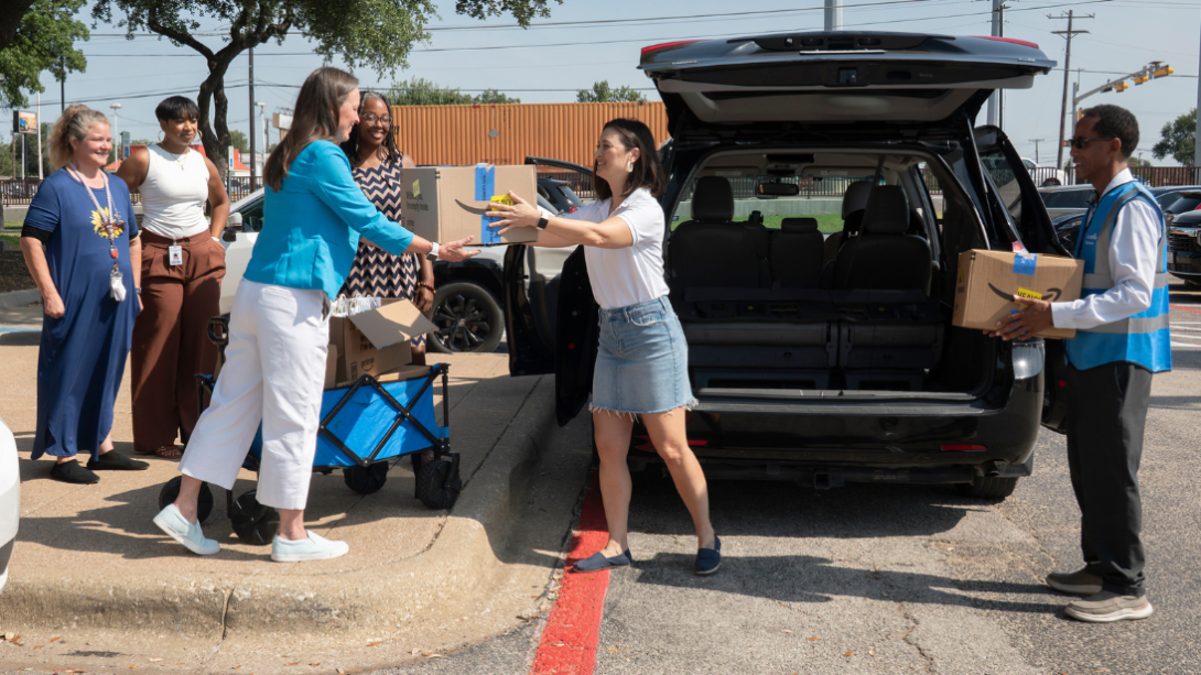 two adults pass cardboard boxes to another adult