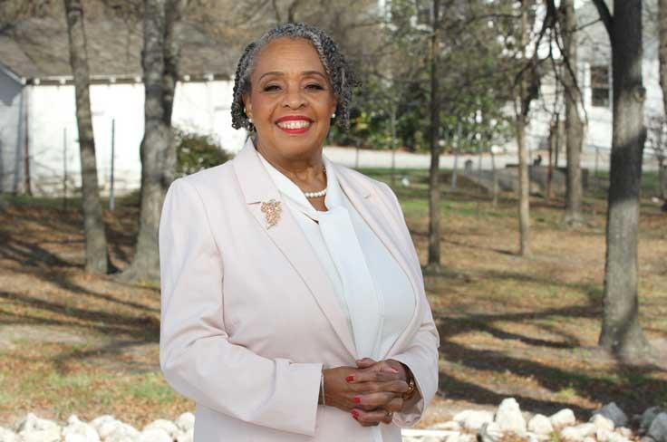 Linda L. Griffin in a white suit with trees in the background